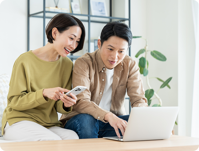 ノートパソコンを見ながら話し合う夫婦